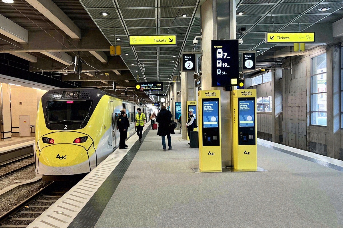 Treno giallo dell'Arlanda Express al binario accanto alle biglietterie automatiche